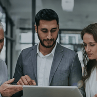 Three professionals reviewing laptop data.