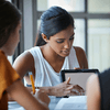 Three women collaborating around a tablet.
