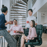 Four coworkers chatting over coffee mugs.