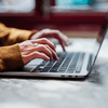 Hands typing on laptop keyboard.