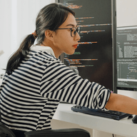 A woman wearing glasses working on her laptopn