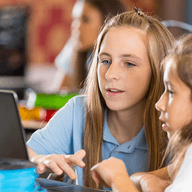 Two kids looking at a laptop