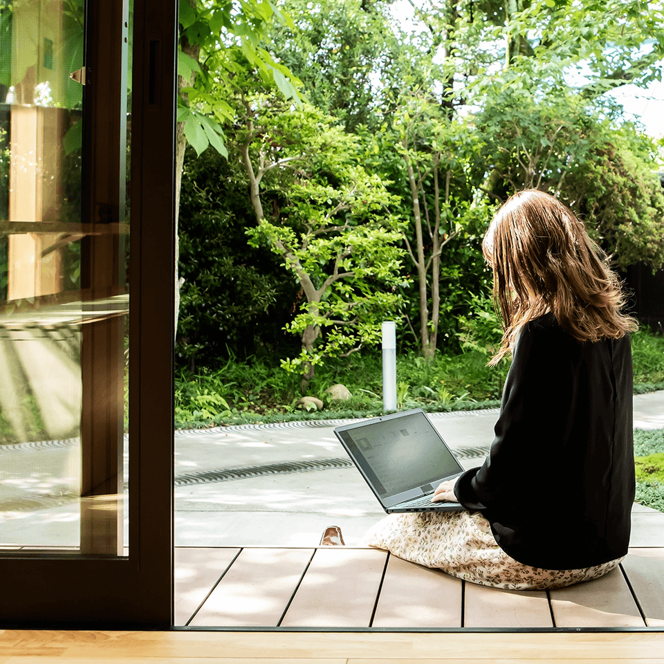 Person working on laptop near greenery.