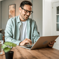 Man smiling while using laptop.