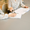 Two woman signing on papers
