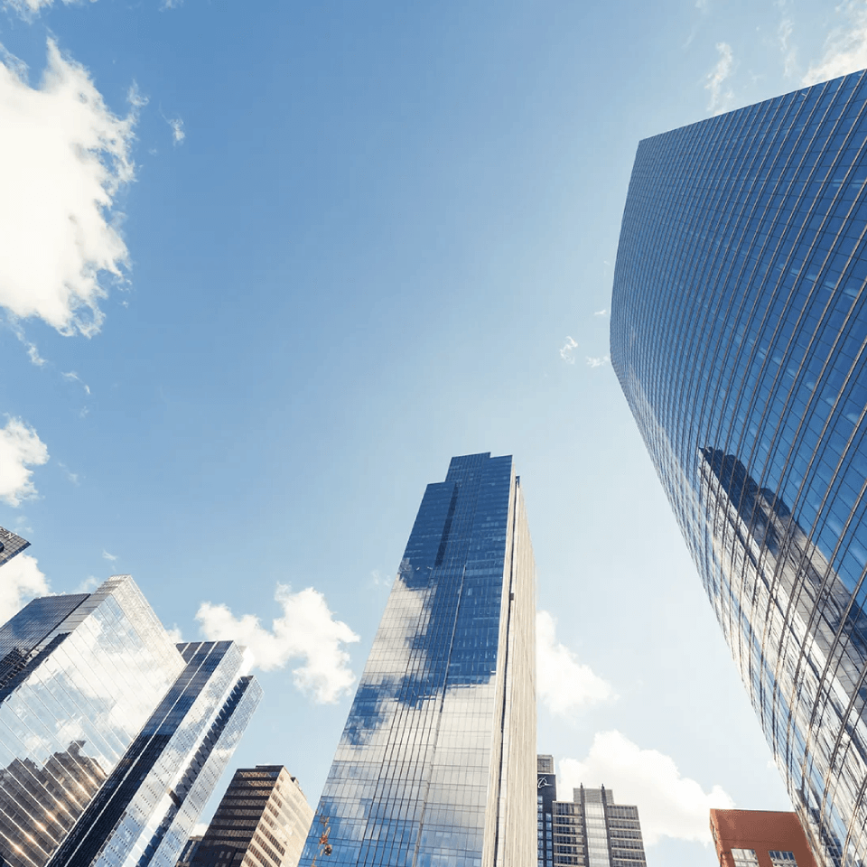A wide angle picture of a CBD aiming for the blue sky with glass skyscrapers on the bottom half of the picture